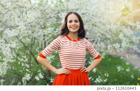 Lovely happy smiling young woman in spring blooming garden with white flowers on the trees in park Lovely happy smiling young woman in spring blooming garden with white flowers on the trees in park 112610443