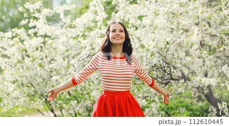 Lovely happy smiling young woman in spring blooming garden with flowers on the trees in park Lovely happy smiling young woman in spring blooming garden with flowers on the trees in park 112610445