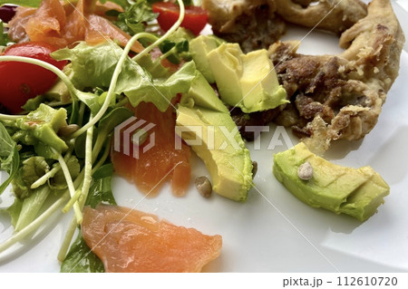 On a white plate - a salad of tomatoes, green arugula, avocado, salmon and mushrooms On a white plate - a salad of tomatoes, green arugula, avocado, salmon and mushrooms 112610720