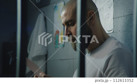 Upset male prisoner looks at pictures of family or kids and cries Upset male prisoner looks at pictures of family or kids and cries 112613352