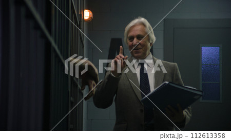 Advocate talks with criminal leaning on prison cell bars Advocate talks with criminal leaning on prison cell bars 112613358