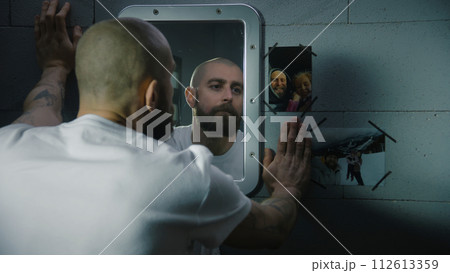 Inmate looks at the pictures with family hanging near the mirror Inmate looks at the pictures with family hanging near the mirror 112613359