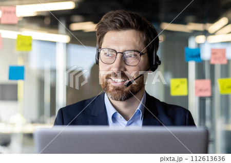 Confident business professional engaging in a video conference call with a headset in a modern office setting. 112613636