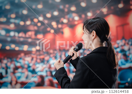 大勢の聴衆の前でスピーチをする女性 大勢の聴衆の前でスピーチをする女性 112614458