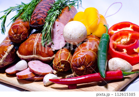 Tasty sausages and vegetables isolated over solid background Tasty sausages and vegetables isolated over solid background 112615385