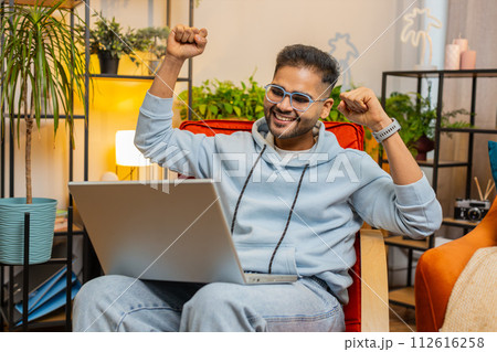 Amazed Indian man use laptop computer, receive good news message shocked by victory, celebrate win Amazed Indian man use laptop computer, receive good news message shocked by victory, celebrate win 112616258