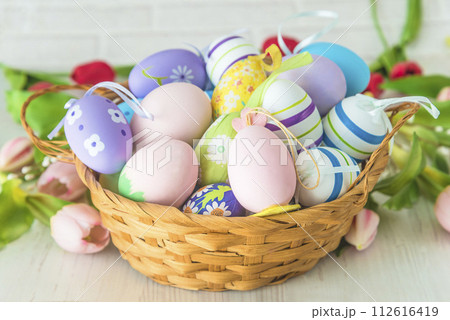 Happy Easter holidays concept; Close up for wicker basket with easter eggs and spring flowers on a white background Happy Easter holidays concept; Close up for wicker basket with easter eggs and spring flowers on a white background 112616419