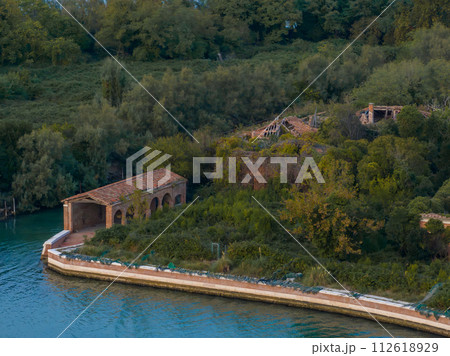 Aerial view of the plagued ghost island of Poveglia in the Venetian lagoon, opposite Malamocco along the Canal Orfano near Venice, Italy. Aerial view of the plagued ghost island of Poveglia in the Venetian lagoon, opposite Malamocco along the Canal Orfano near Venice, Italy. 112618929