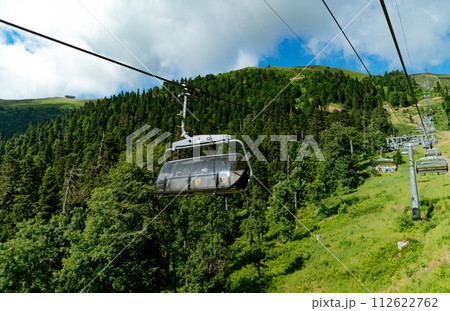Modern rope way cabins with people against blue sky and mountain tops. Rosa Khutor, Soschi, Russia 112622762
