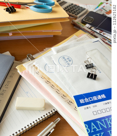 溜まった書類や郵便物が散乱した机 散らかった机 雑然 溜まった書類や郵便物が散乱した机 散らかった机 雑然 112625182