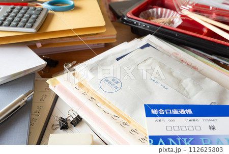 溜まった書類や郵便物で散乱した部屋　散らかった机　雑然 112625803