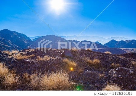 rocks and dry grass tufts in autumn mountains backlit scene at sunny day 112626193