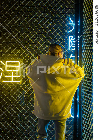Beautiful blonde woman in white hoodie and blue jeans posing against neon background Beautiful blonde woman in white hoodie and blue jeans posing against neon background 112626686