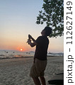 夕暮れのビーチでシャンパンを開けてお祝い 112627149