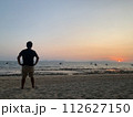 ビーチでサンセットを見る男性 112627150