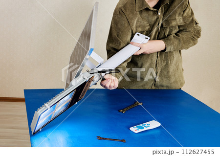 Handyman installs solar module on arm holder for standalone cordless LED street light. 112627455