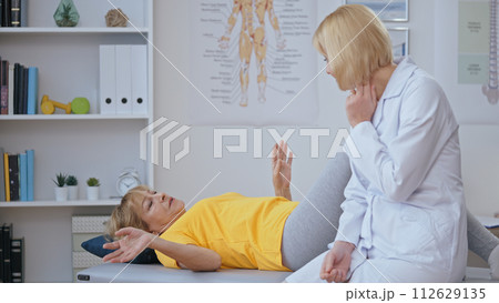 An elderly woman patient discusses her chronic joint pain while being examined by an orthopedist An elderly woman patient discusses her chronic joint pain while being examined by an orthopedist 112629135