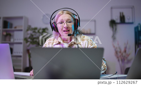 Senior woman gamer commenting video game, taking part in an online tournament from home office 112629267