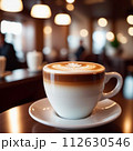 Cup of coffee in cafe. Anamorphic bokeh effect. Tilt-shift photo. Hot coffee in a white cup. The coffee is getting cold. Aroma of coffee beans. Label or advertisement. Foam. 112630546