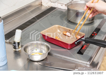 お弁当のウィンナーを焼く女性の手元 112631807