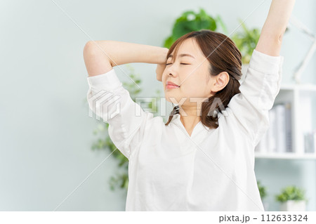 部屋で伸びをする女性 112633324