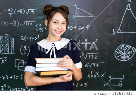 A schoolgirl girl with books and textbooks in her hands, a teenage girl 10-12 years old in a school class A schoolgirl girl with books and textbooks in her hands, a teenage girl 10-12 years old in a school class 112633433