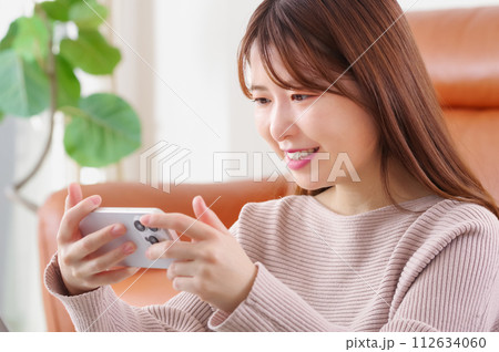 笑顔でスマートフォンを見つめる女性 112634060