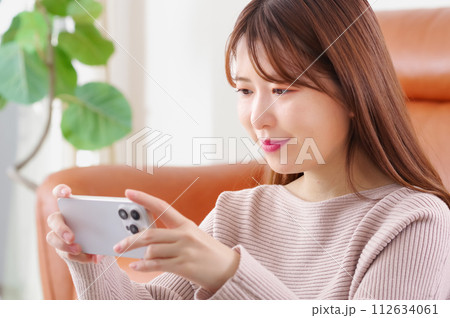 笑顔でスマートフォンを見つめる女性 笑顔でスマートフォンを見つめる女性 112634061
