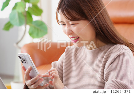 スマホを見て険しい表情をする女性 スマホを見て険しい表情をする女性 112634371