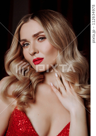 Blonde woman model in a red dress on a black background. Blonde woman model in a red dress on a black background. 112634978
