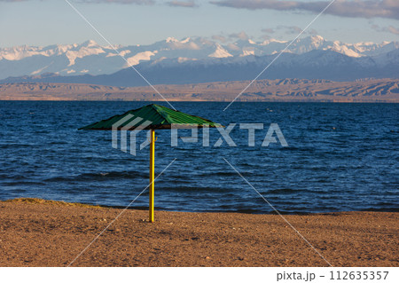 rigid steel umbrella on beach of mountain lake at sunny evening 112635357