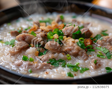 Close-up of steaming bowl of pork congee garnished with fresh green onions. Generative AI. 112636075