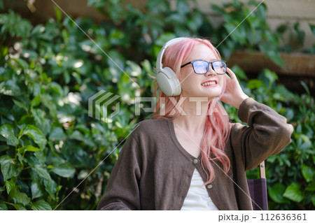 A cute pink-haired girl drawing on a digital tablet and wearing headphones in the garden, a Woman Doing Freelance Work in the Garden, and a woman with a digital tablet with artwork. A cute pink-haired girl drawing on a digital tablet and wearing headphones in the garden, a Woman Doing Freelance Work in the Garden, and a woman with a digital tablet with artwork. 112636361