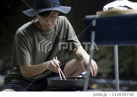 フライパンで食材を炒める男性　アウトドアイメージ 112636736