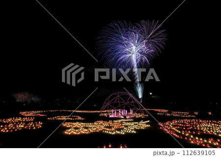 梅祭り期間中の夜の偕楽園に並べられたキャンドルと、その向こうに広がる鮮やかな打ち上げ花火 112639105