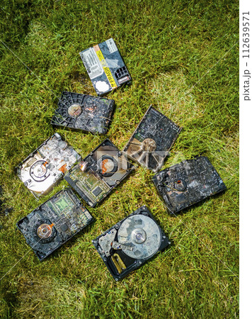 Burned hard drives lying on the green lawn 112639571
