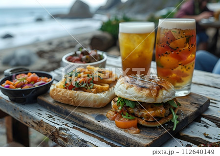 Illustration of delicious looking food beautifully arranged on a beach by the sea. Can be used to attract tourists, promote seaside restaurants, food products, catering services or travel packages 112640149