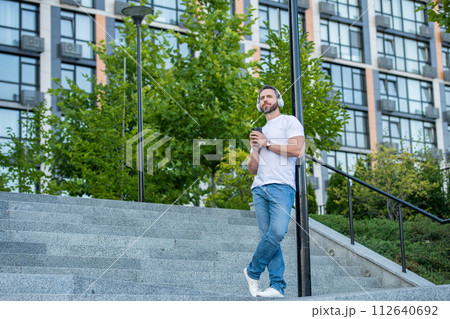 man in music headphones outside, advertisement. photo of man in music headphones with coffee 112640692