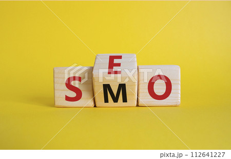 SEO vs SMO symbol. Wooden cubes with words SMO and SEO. Beautiful yellow background. SEO vs SMO and business concept. Copy space 112641227