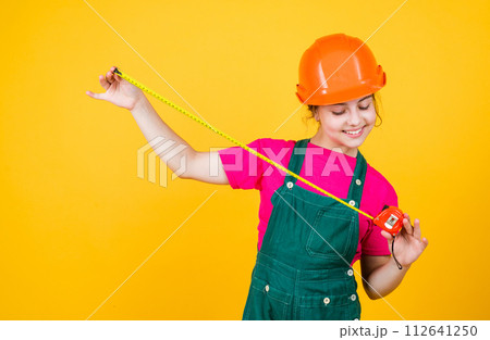 size. teen girl in hard hat and uniform. building and construction. concept of repair. Little girl using a measuring tape. engineer. happy child hold tape measure. kid builder wear helmet size. teen girl in hard hat and uniform. building and construction. concept of repair. Little girl using a measuring tape. engineer. happy child hold tape measure. kid builder wear helmet 112641250