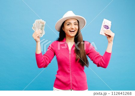 Happy traveler tourist woman holding tickets and money bills isolated on blue background studio. Passenger travel abroad on weekends. 112641268