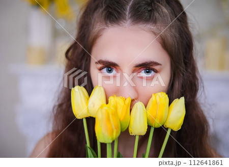 Close-up of a girl's eyes with yellow tulips. Spring thoughtful mood 112641861