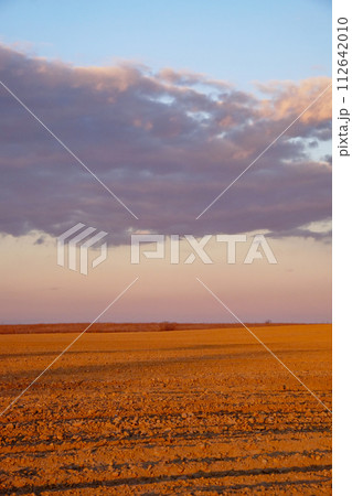 The image captures rocks on ground with clouds in the distant sky. The image captures rocks on ground with clouds in the distant sky. 112642010