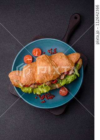 Delicious fresh crispy croissant with chicken or beef meat, lettuce, tomatoes, spices and sauce Delicious fresh crispy croissant with chicken or beef meat, lettuce, tomatoes, spices and sauce 112642366
