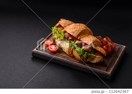 Delicious fresh crispy croissant with chicken or beef meat, lettuce, tomatoes, spices and sauce Delicious fresh crispy croissant with chicken or beef meat, lettuce, tomatoes, spices and sauce 112642367