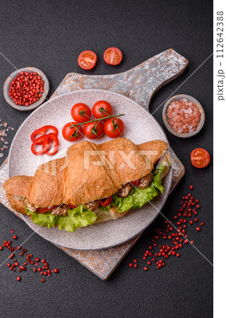 Delicious fresh crispy croissant with chicken or beef meat, lettuce, tomatoes, spices and sauce 112642388