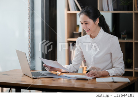 Portrait of Young Successful Asian Businesswoman Sitting at Desk Working on Laptop Computer in Office. Ambitious Corporate Manager Plan Investment Strategy for e-Commerce Project. 112644193