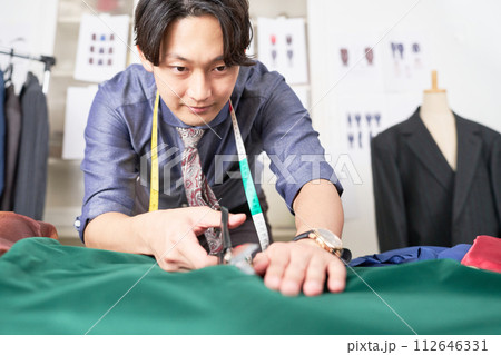 生地をカットする紳士服デザイナー 112646331