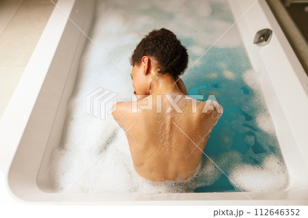 Man leisurely bathing in foamy water in bathtub for fun and recreation 112646352