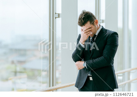 駅・ターミナル・ビルでトラブルで悩むスーツ姿の外国人ビジネスマン（考える・悩む・困る） 112646721